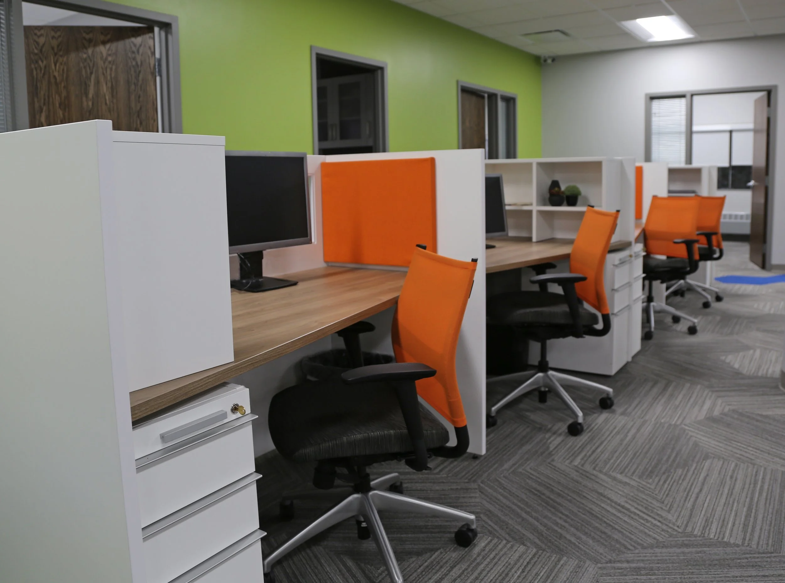 White and Tuscany color linear workstations with orange mesh backed chairs and accent on workstations