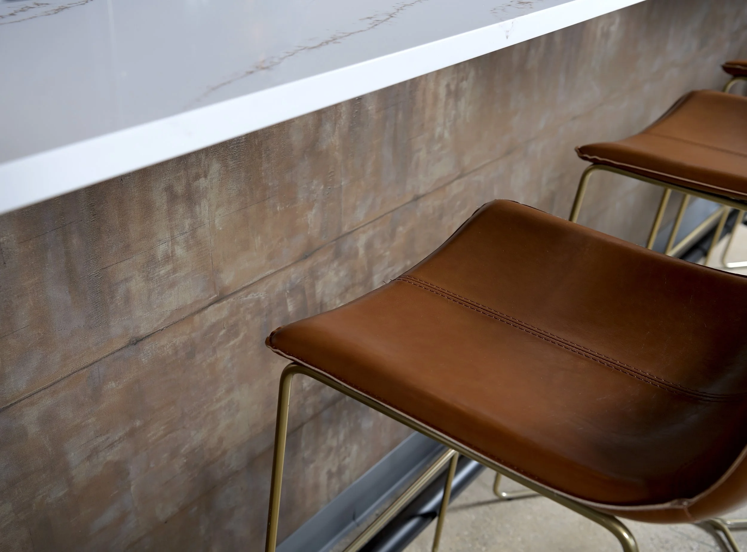 Close up of bar stools in front of a wood texture wallcovering