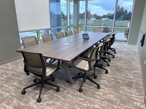 Walnut finish sawhorse legs conference table in conference room with lots of windows