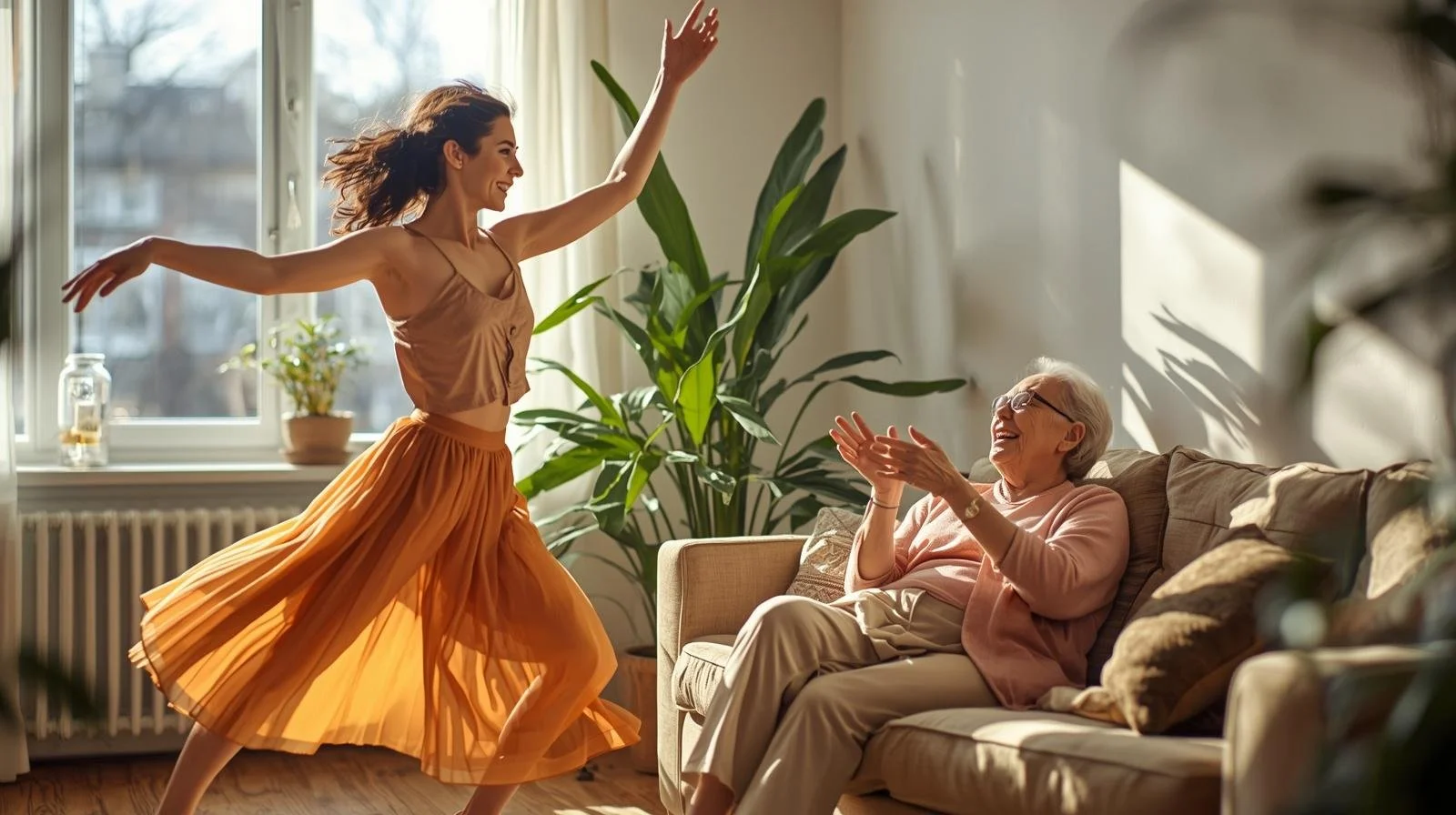 A young woman is dancing joyfully in a sunlit living room while an elderly woman, sitting on a sofa, smiles and claps in delight.