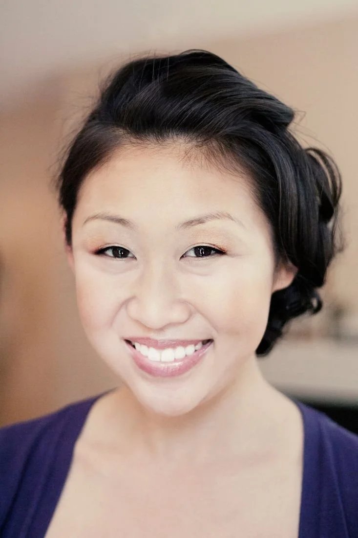 Smiling woman with her dark hair pinned up and soft, natural make up