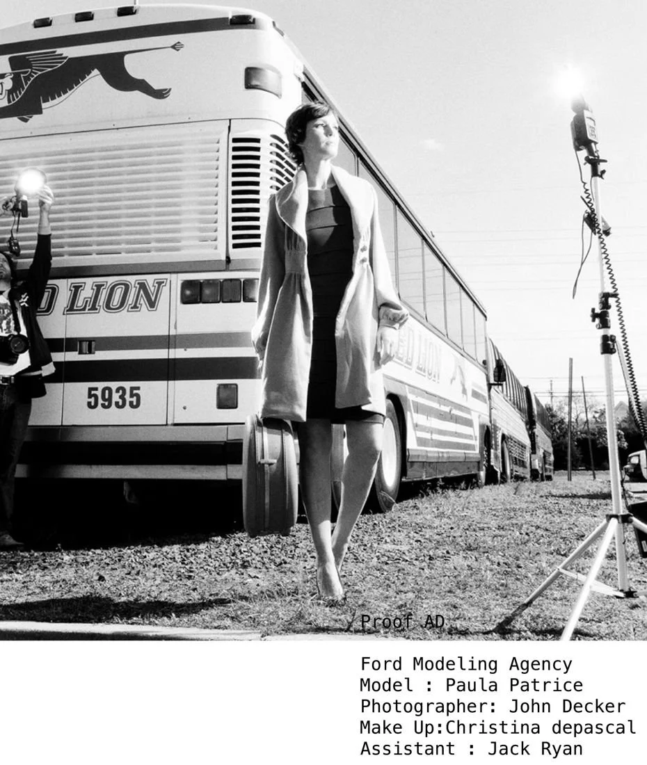 Black and white photo of a woman standing in front of a bus