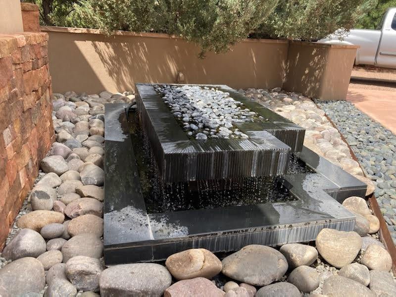 Black granite fountain for private residence in Santa Fe, fabricated and installed in 2012 with hundreds of hand-cut grooves at varying depths to angle the flow of water. (Photo taken during a drought when owner was conserving water.)