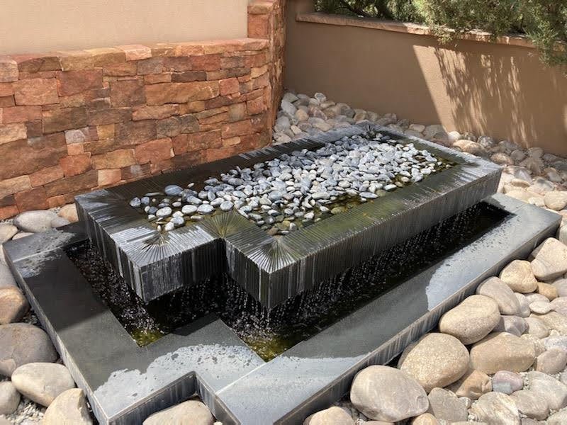 Black granite fountain for private residence in Santa Fe, fabricated and installed in 2012 with hundreds of hand-cut grooves at varying depths to angle the flow of water. (Photo taken during a drought when owner was conserving water.)