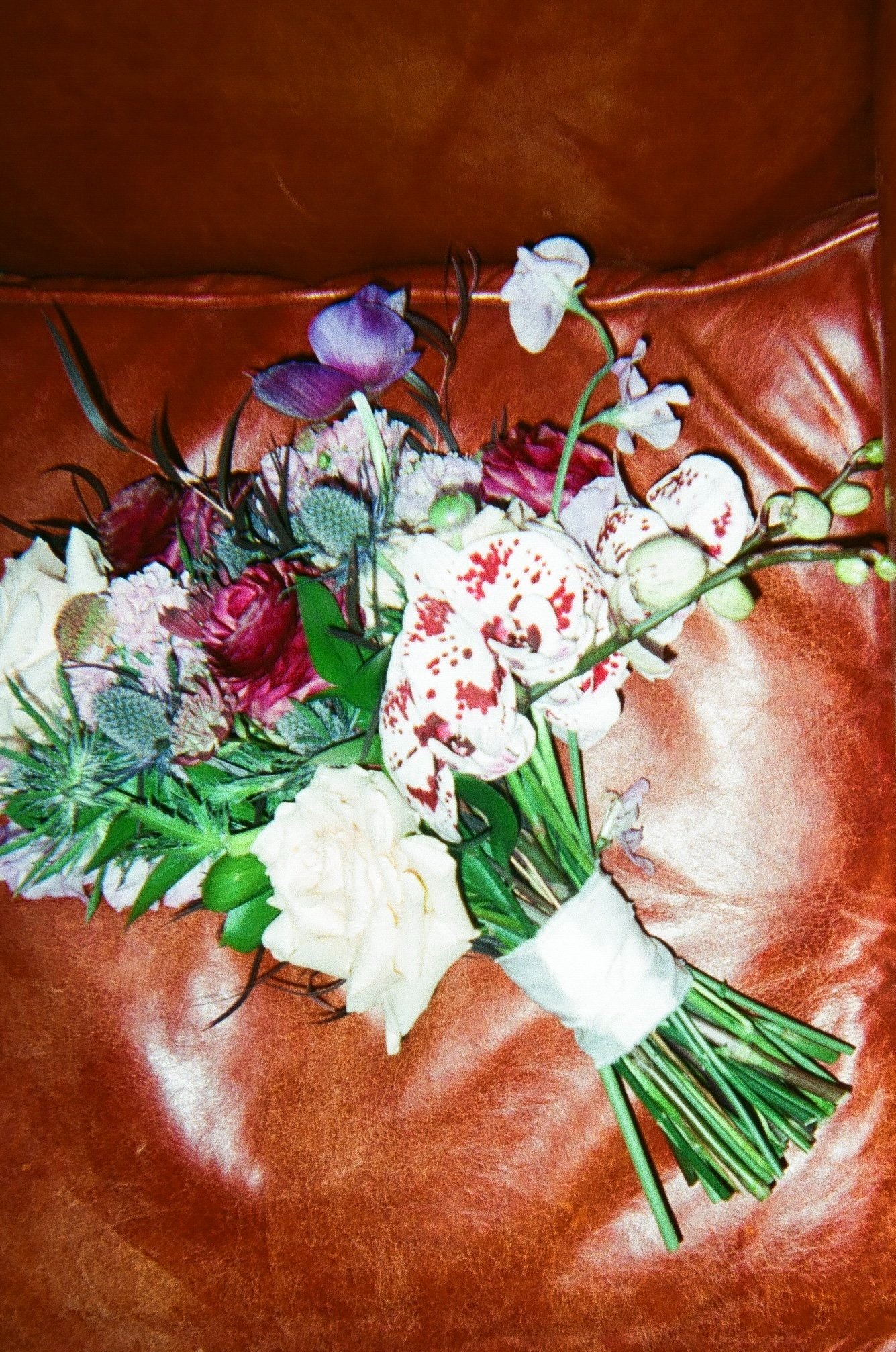 A colorful bouquet of assorted flowers on a brown leather surface.