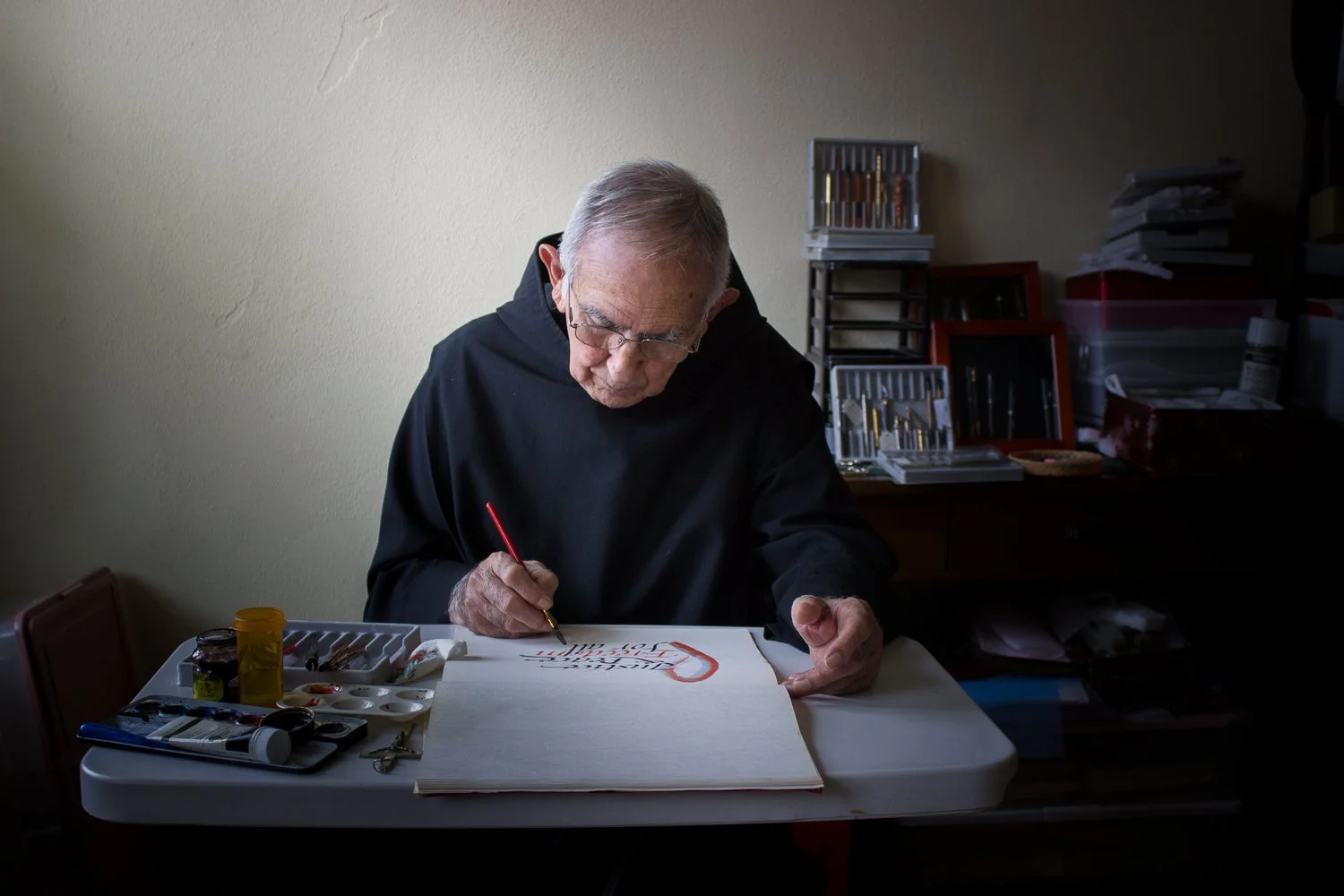 Monk holding paintbrush working on calligraphy