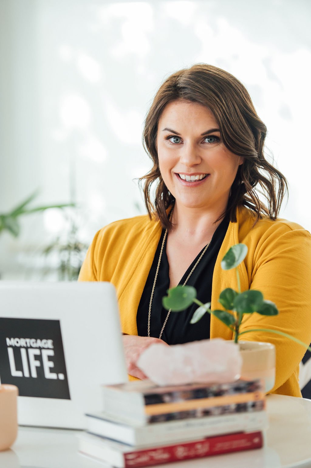 Business brand photography of a businesswoman at her desk with a laptop and a plant.