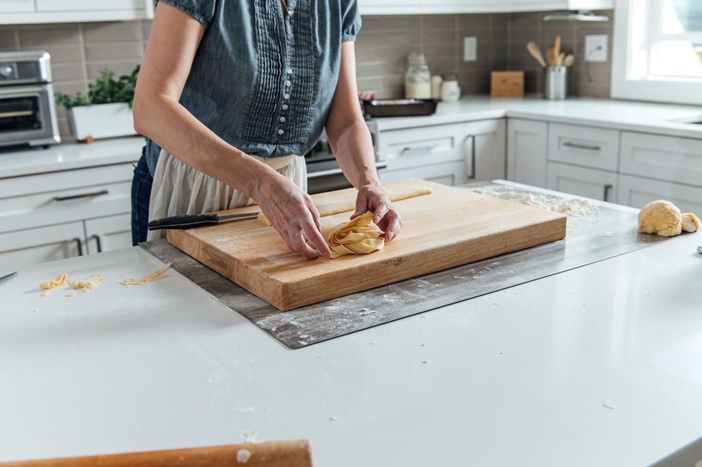 A personal brand photographer captures a woman slicing bread on a cutting board
