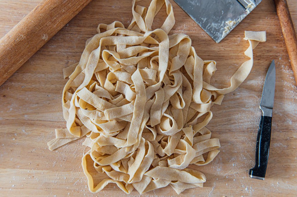 Professional branding photographer capturing fettuccine on a cutting board with a knife during a food shoot