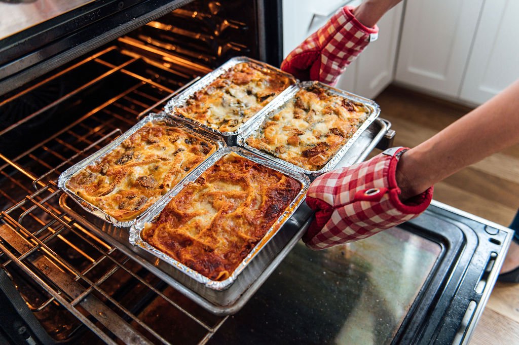 A personal food brand photographer captures a woman as she removes lasagna from the oven at STEFANIA’S KITCHEN - PORTLAND, OR
