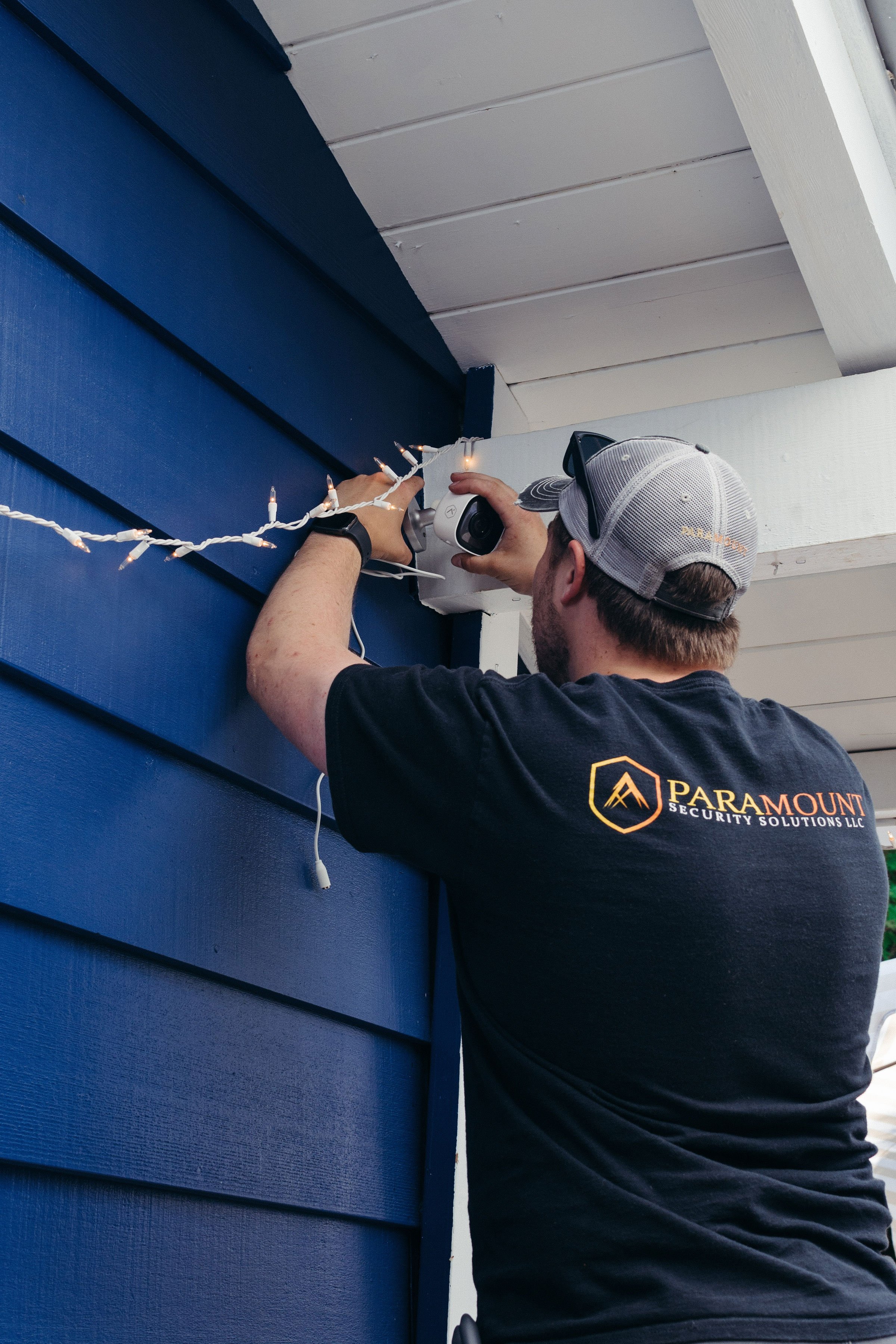 A worker installs a security camera on a house in this corporate branding photograph for brand workers in Portland