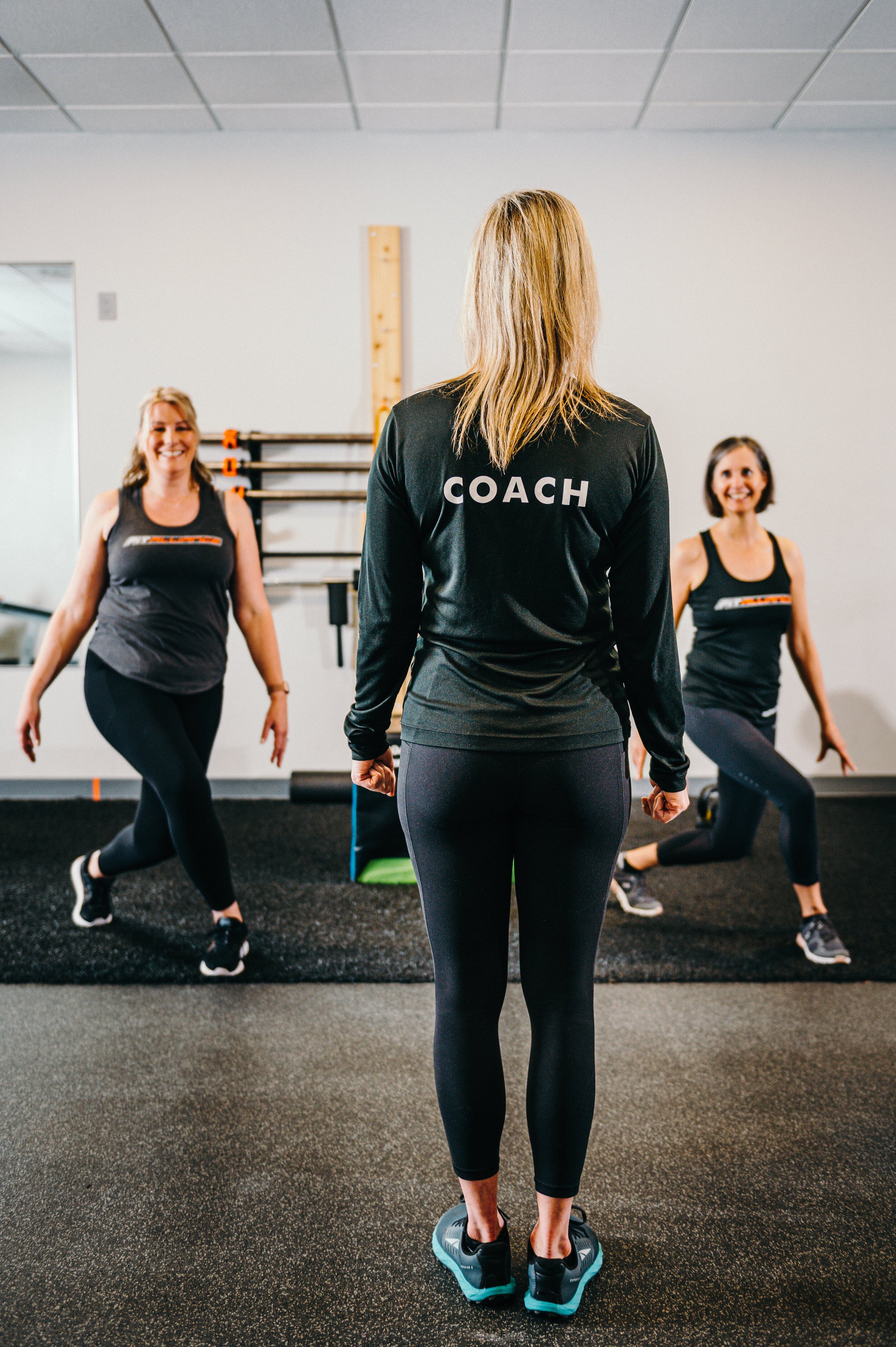 A group of women in a FIT ALLIANCE  gym, led by a coach photographed by a Portland branding photographer