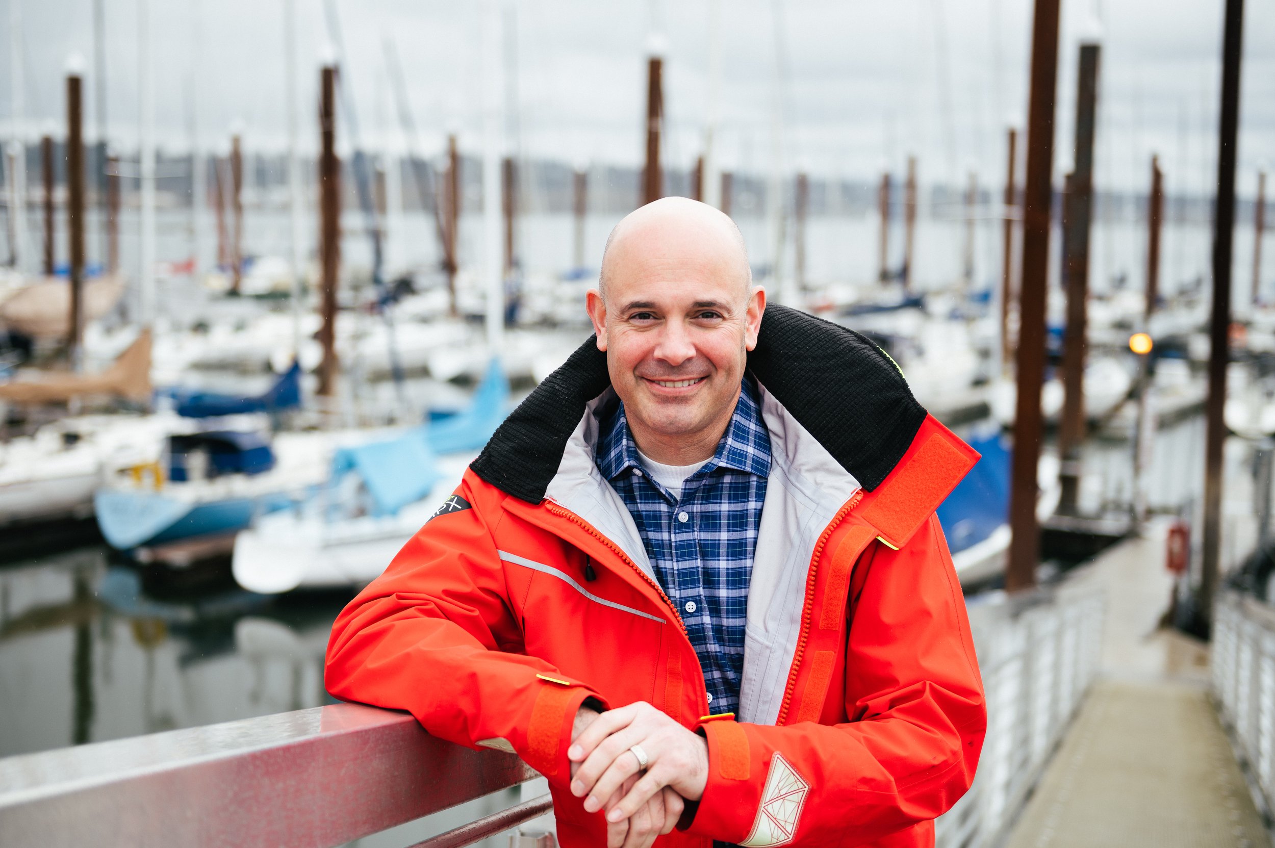 A businessman in an orange jacket near boats, captured by a personal brand photographer in Portland