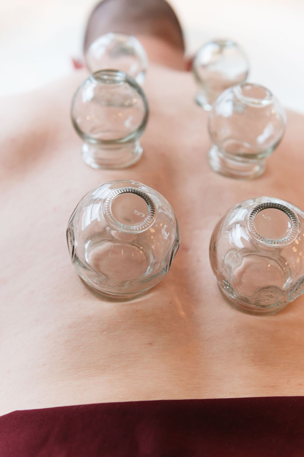 A man lying on his back with four glass jars on his back. Captured in a Portland brand photography.