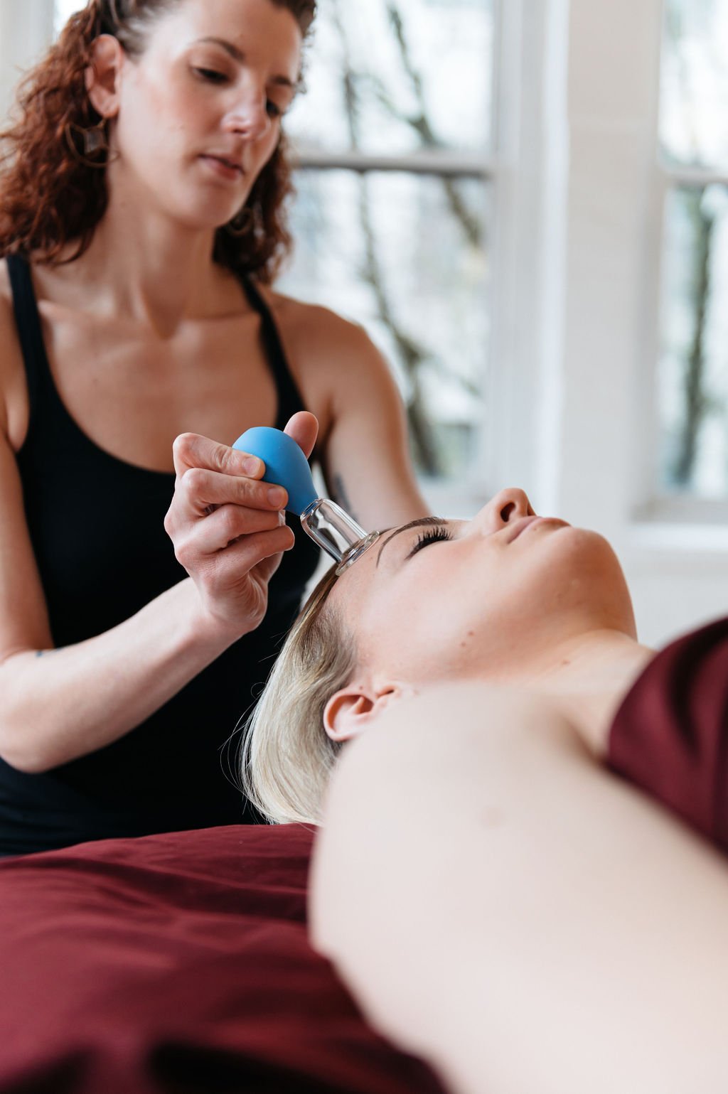 A woman receiving a massage with a blue device. Captured by a brand photographer in Portland.