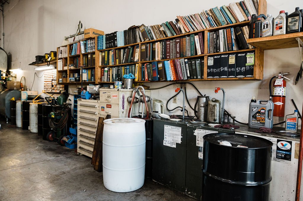 A workshop with shelves, auto repair tools, and large barrels in an Automotives Repair Company