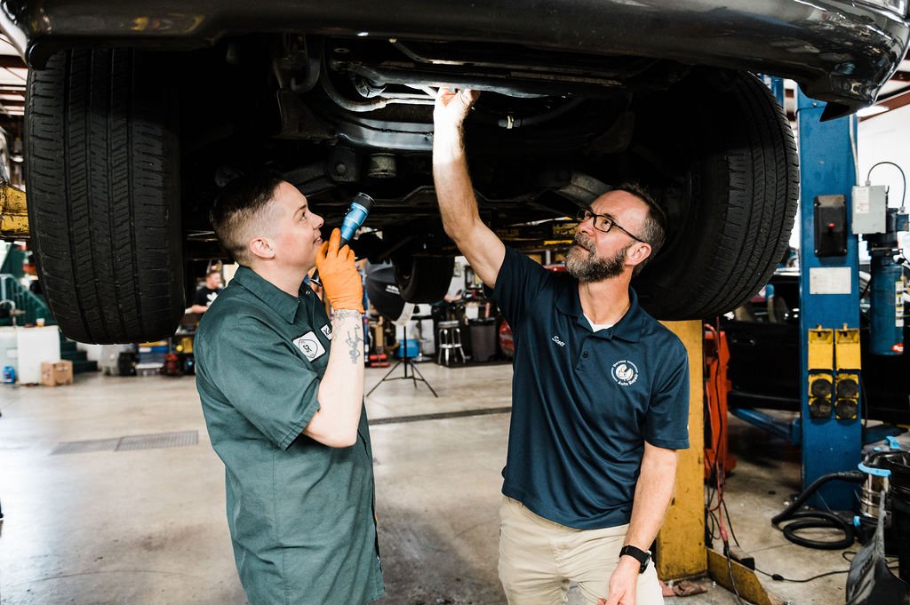 Two technicians inspecting a vehicle in a well-equipped garage captured by a professional branding photographer.