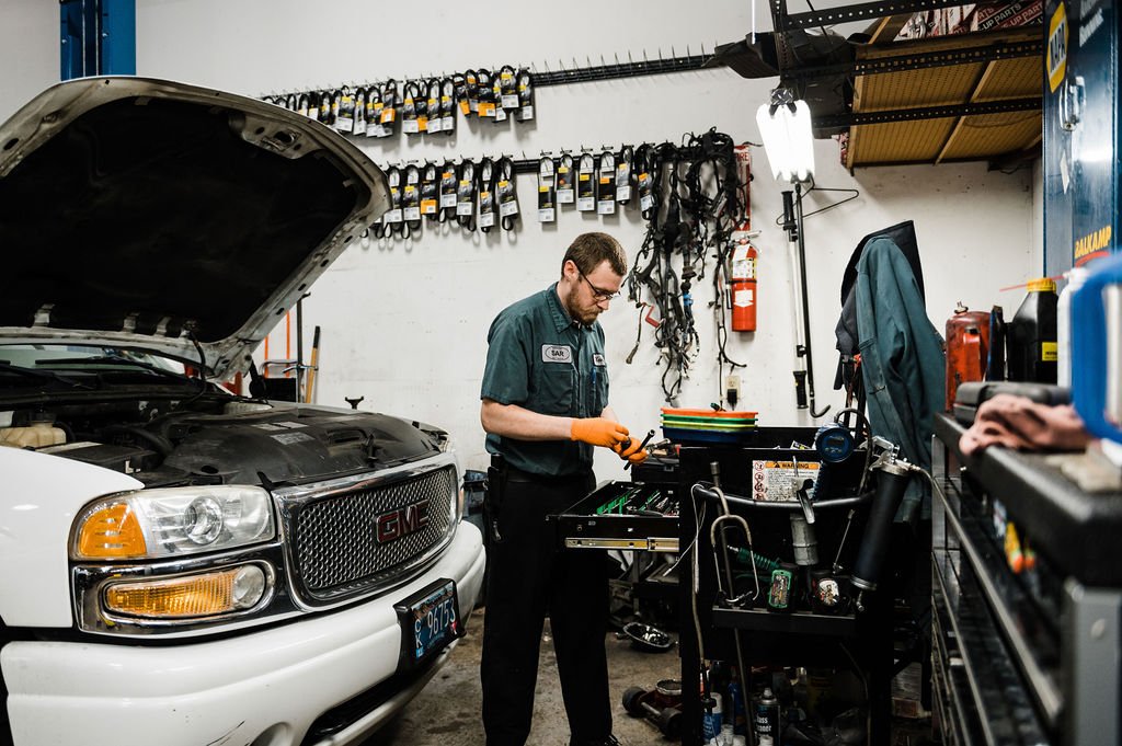 A man showcasing his expertise as he works on a car in an Auto Repair Workshop during a personal branding photoshoot.