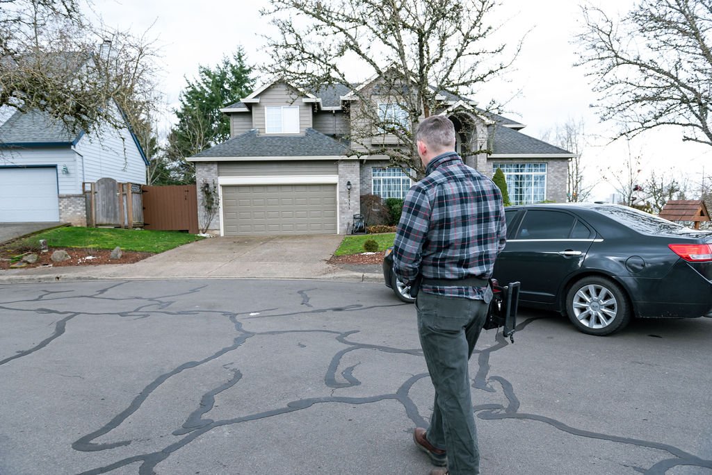 A professional from CDO INSPECTIONS company stands in front of a house captured by a Portland branding photographer. 