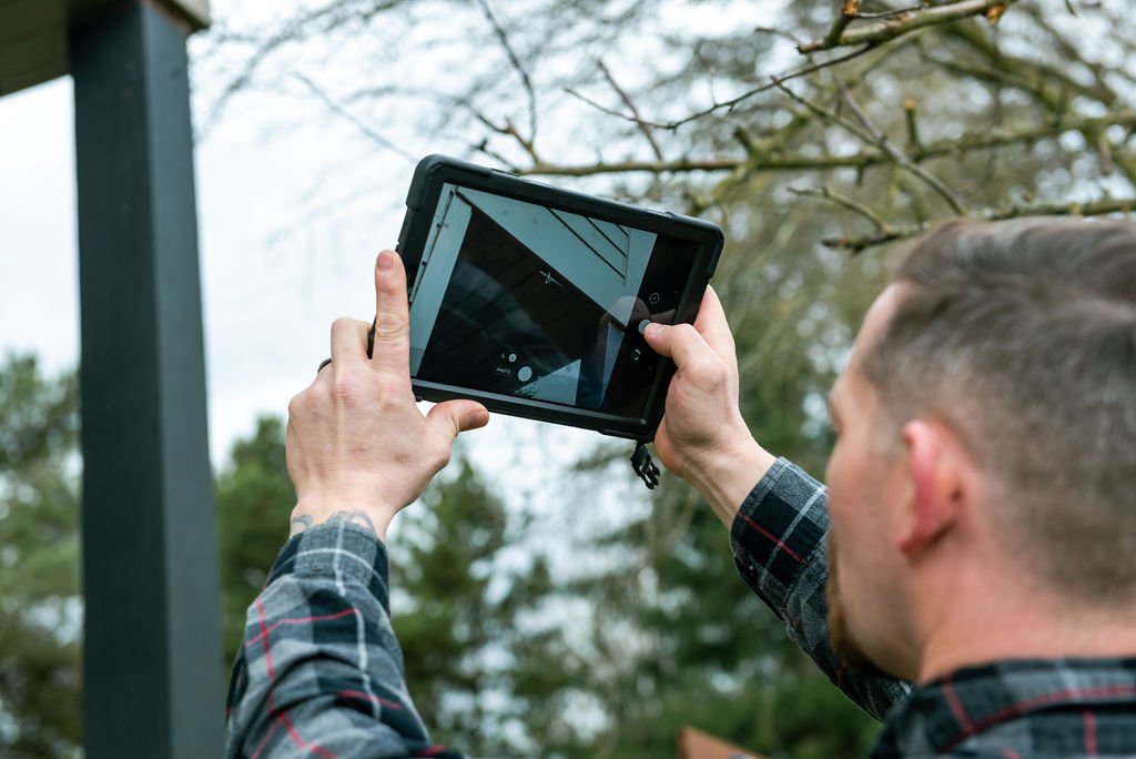 An inspector from CDO Inspections, holding a tablet inspecting a property with trees in the background.