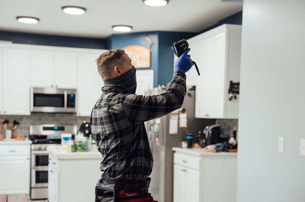 A CDO inspection company skilled worker, donning a mask and gloves, doing an inspection of a kitchen.