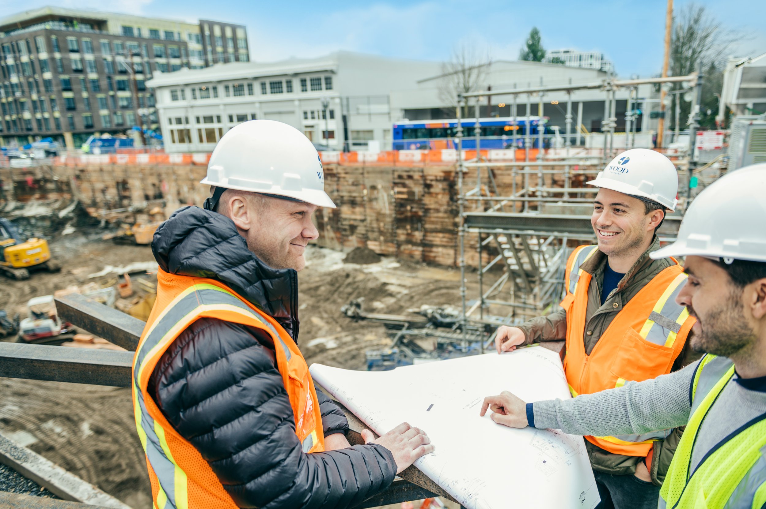 Three men in hard hats and safety vests at a construction site during a brand photoshoot in Portland.