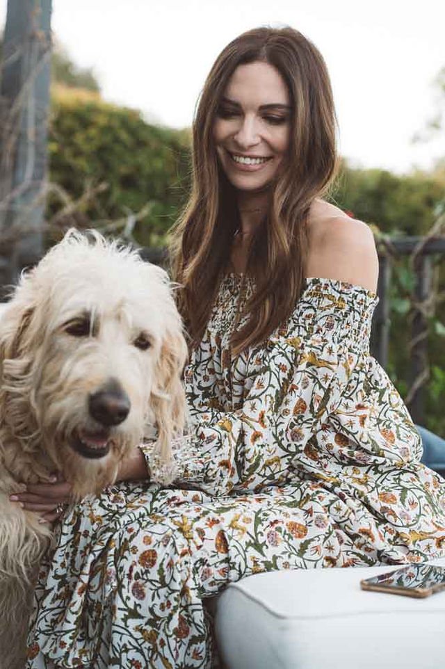 A brand photographer from Portland captures a model in a branded floral dress sitting on a bench with her dog.