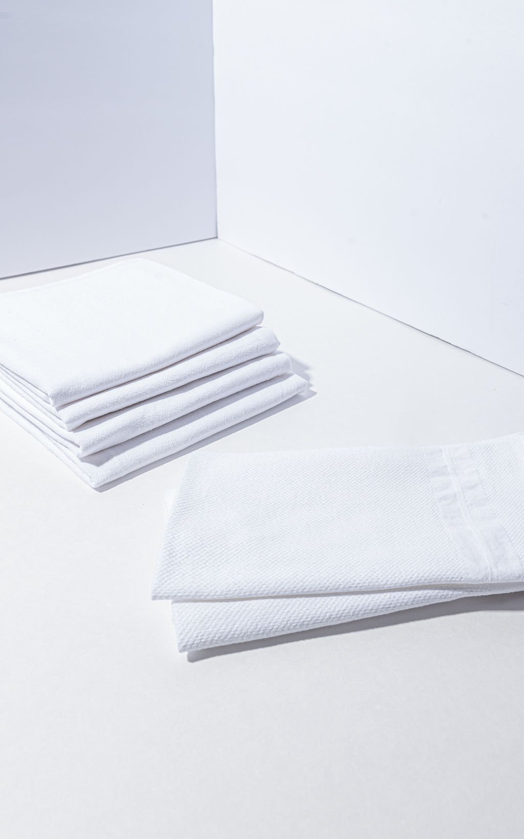 White napkins by ALT brand arranged in a stack on a white surface captured by Portland branding photographer.