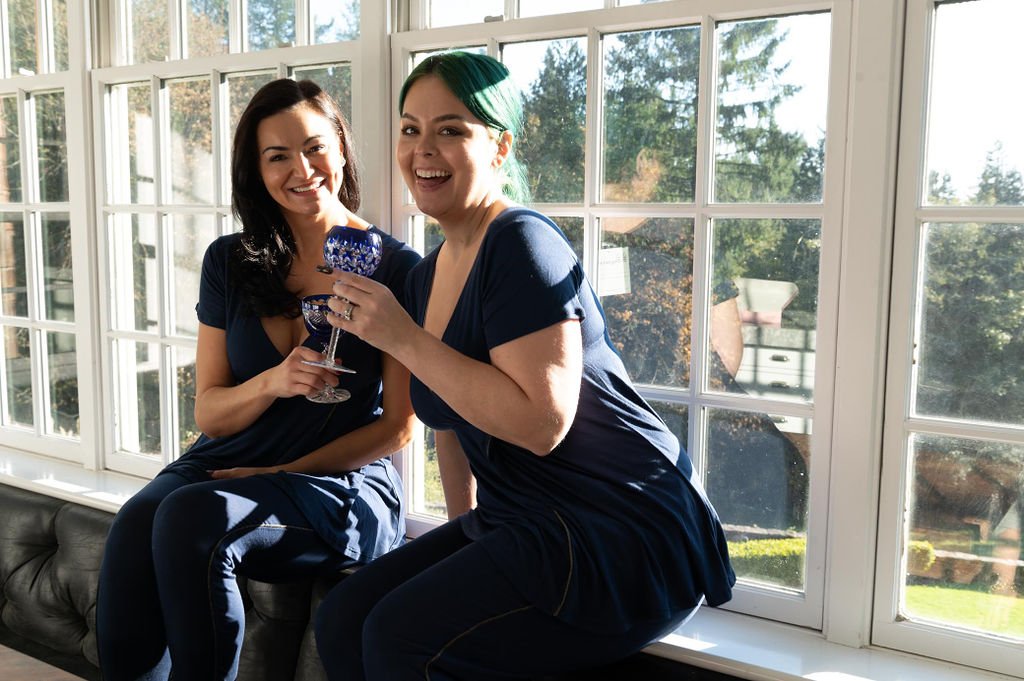 Two expectants in blue Pregjama dresses sitting on a window sill, enjoying a peaceful moment together.