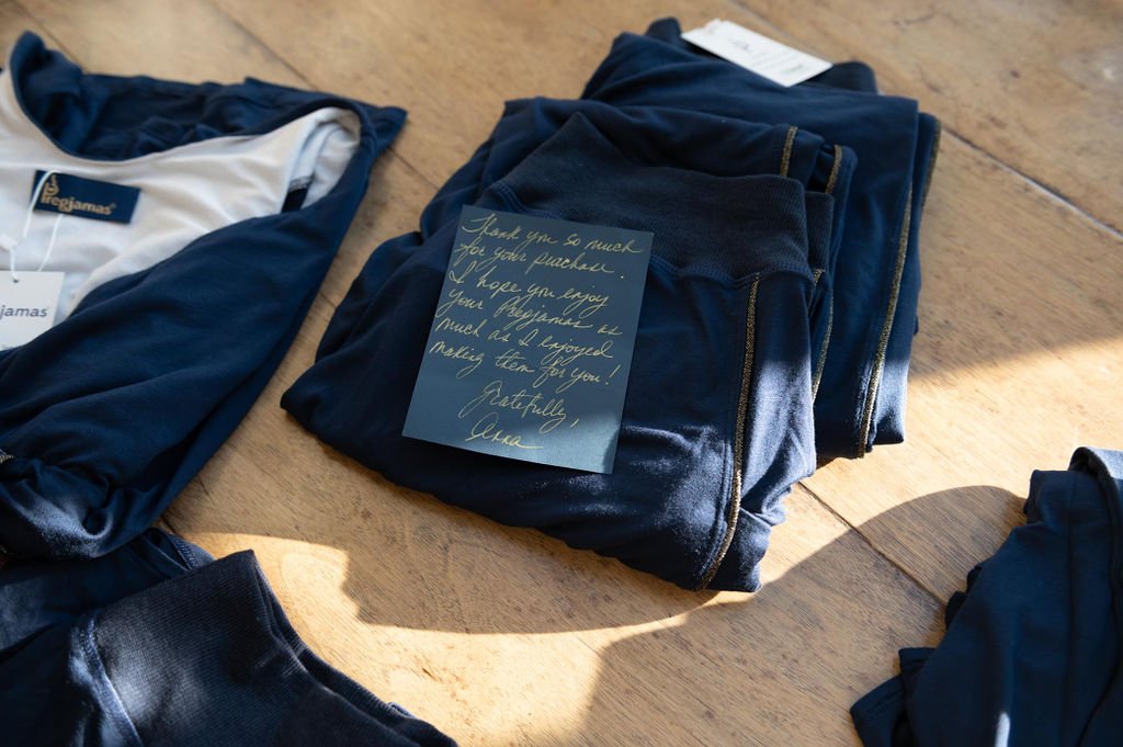 A clothing brand's photography displays a collection of blue and black garments arranged on a wooden table