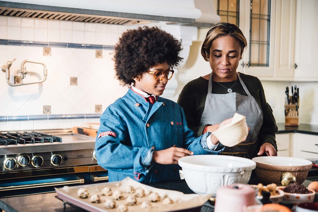 A female chef and a boy joyfully baking cookies together in a kitchen filled with the aroma of freshly baked treats