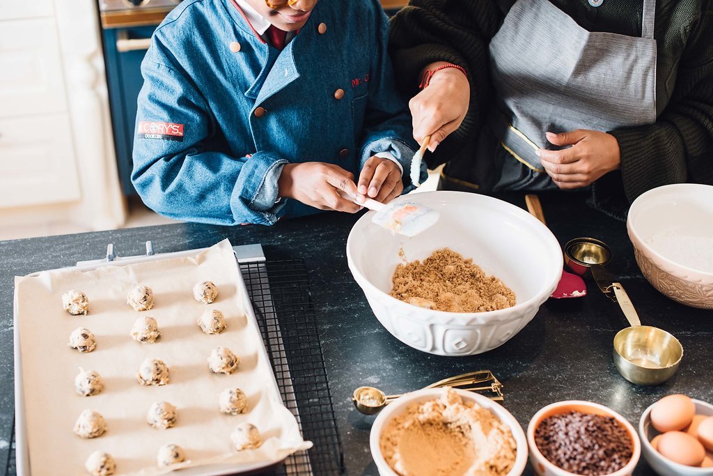 In a kitchen for a food brand photoshoot, two individuals are seen making delicious cookies.