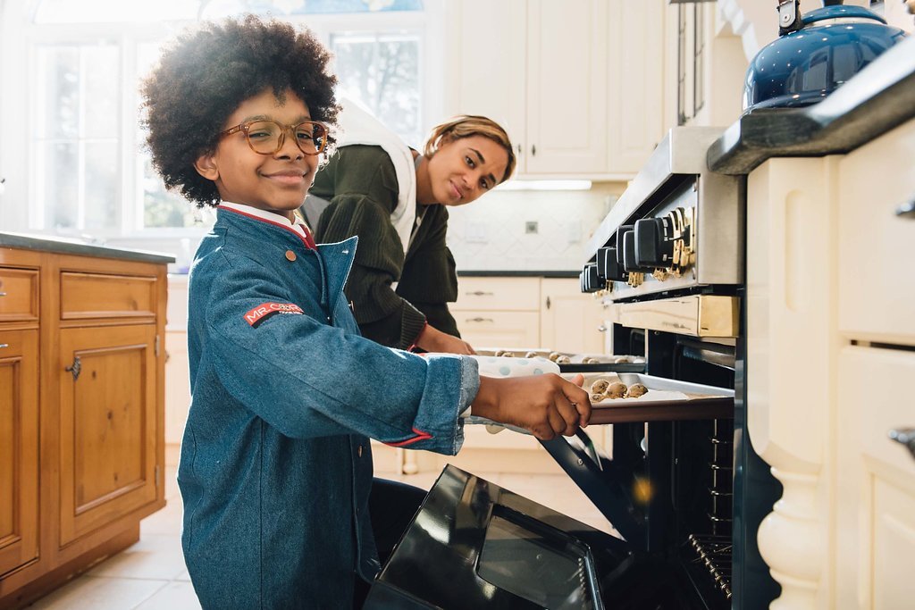 Personal branding photo featuring a woman and child standing near an oven to bake in a kitchen.