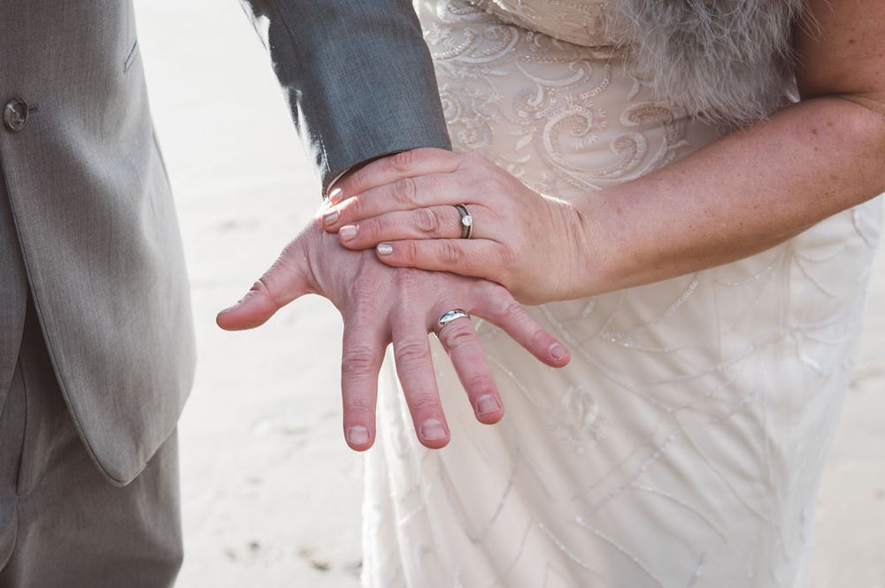 A beautiful bride and groom holding hands on the beach, captured by the best wedding.jpg