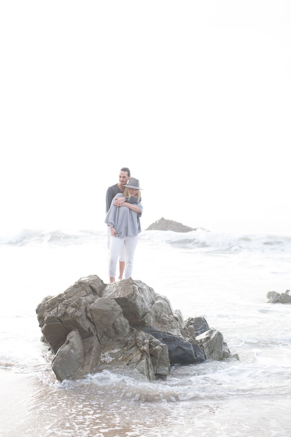 A personal event photographer capturing a Couple standing on an ocean rock.jpg