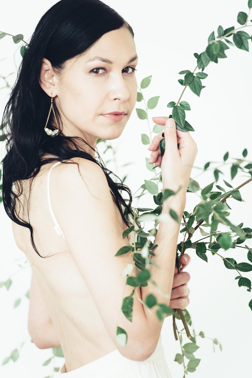 A woman in a white dress gracefully holds a plant, showcasing elegance and nature&#39;s beauty.jpg