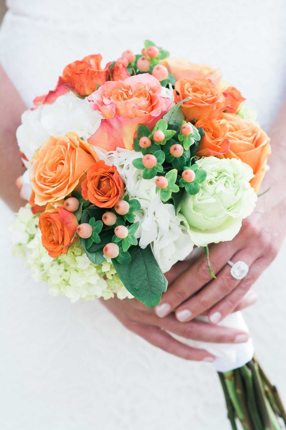 Bride holding orange and white flower bouquet on her wedding day posing for an event.jpg