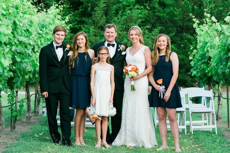 The wedding party smiles in front of the vineyard. Captured by the best family event.jpg