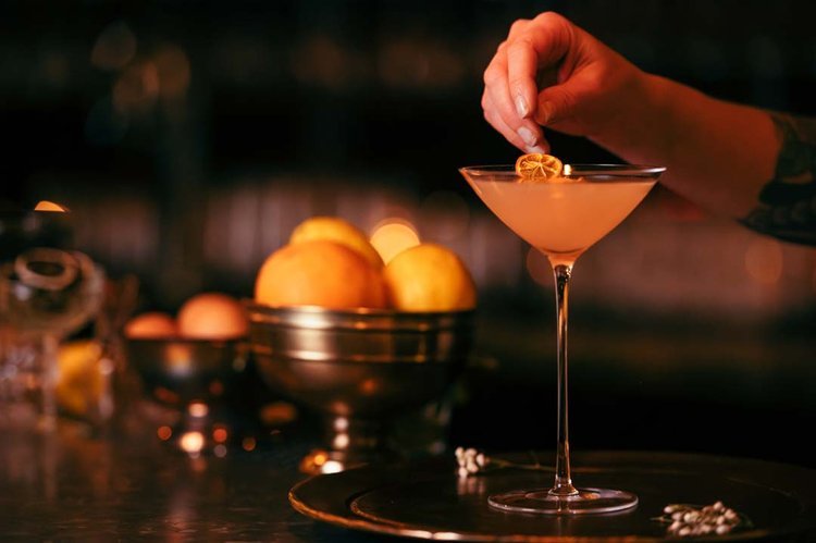 A bartender holding a lemon-filled cocktail, showcasing their mixology skills. Captivating drink photography.jpg