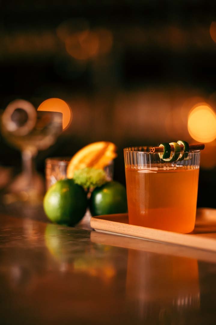 A refreshing cocktail on a wooden tray, garnished with lime and orange Captured in the drink photography.jpg