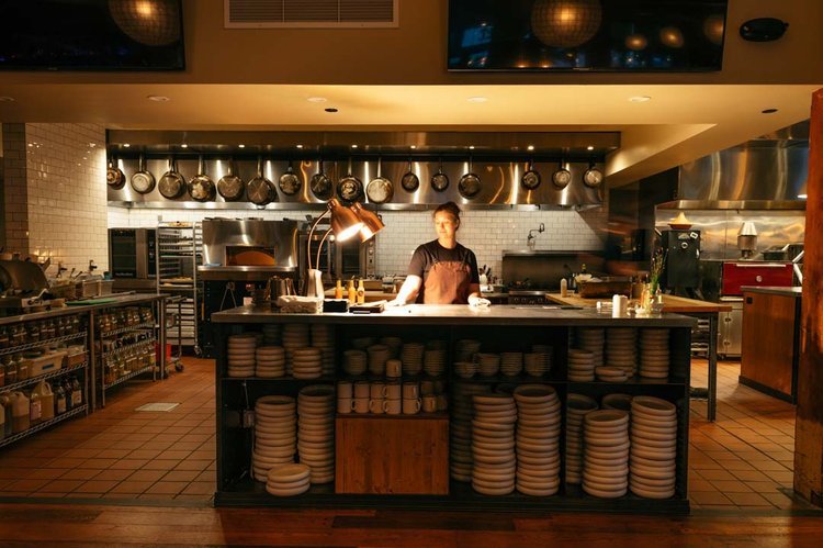 A skilled chef in a restaurant kitchen, surrounded by pots and pans on the counter. Captured by the best restaurant food photographer in Portland.jpg