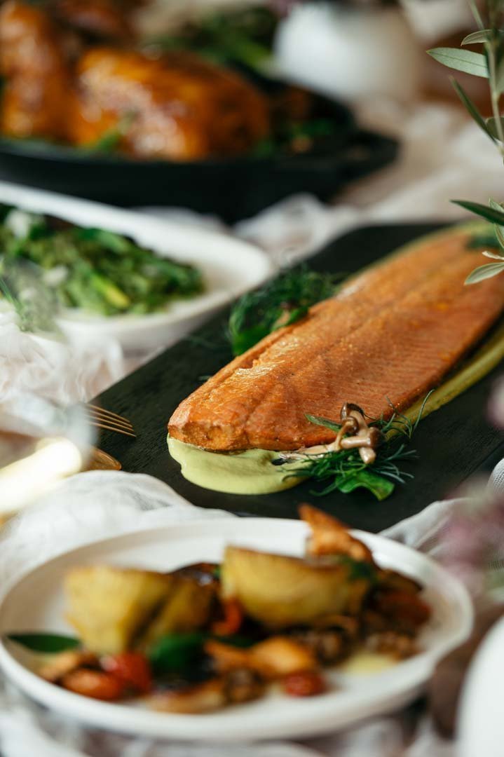 A table with a variety of food dishes, including a plate of deliciously cooked salmon.jpg