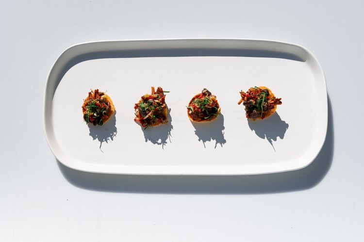 A white plate with four small canapé, beautifully arranged for food photography in Portland.jpg