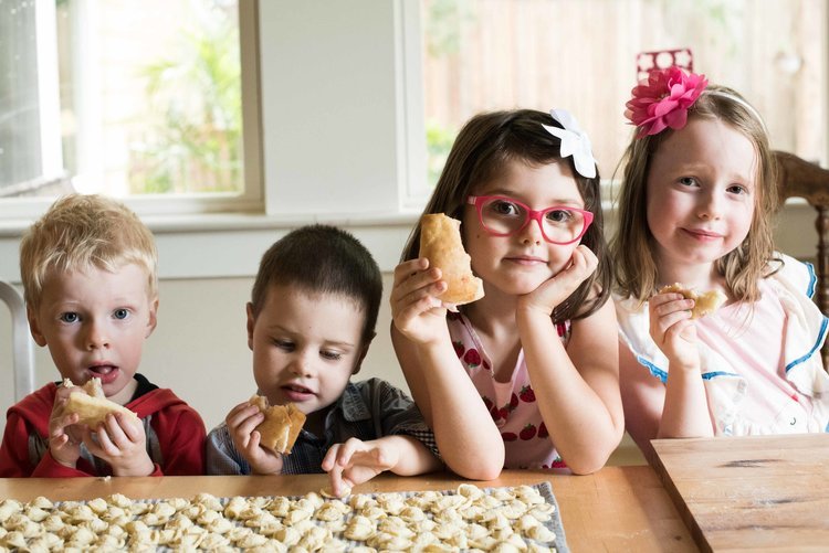 An endearing food photography featuring four children sitting at a table, relishing their meal together.jpg