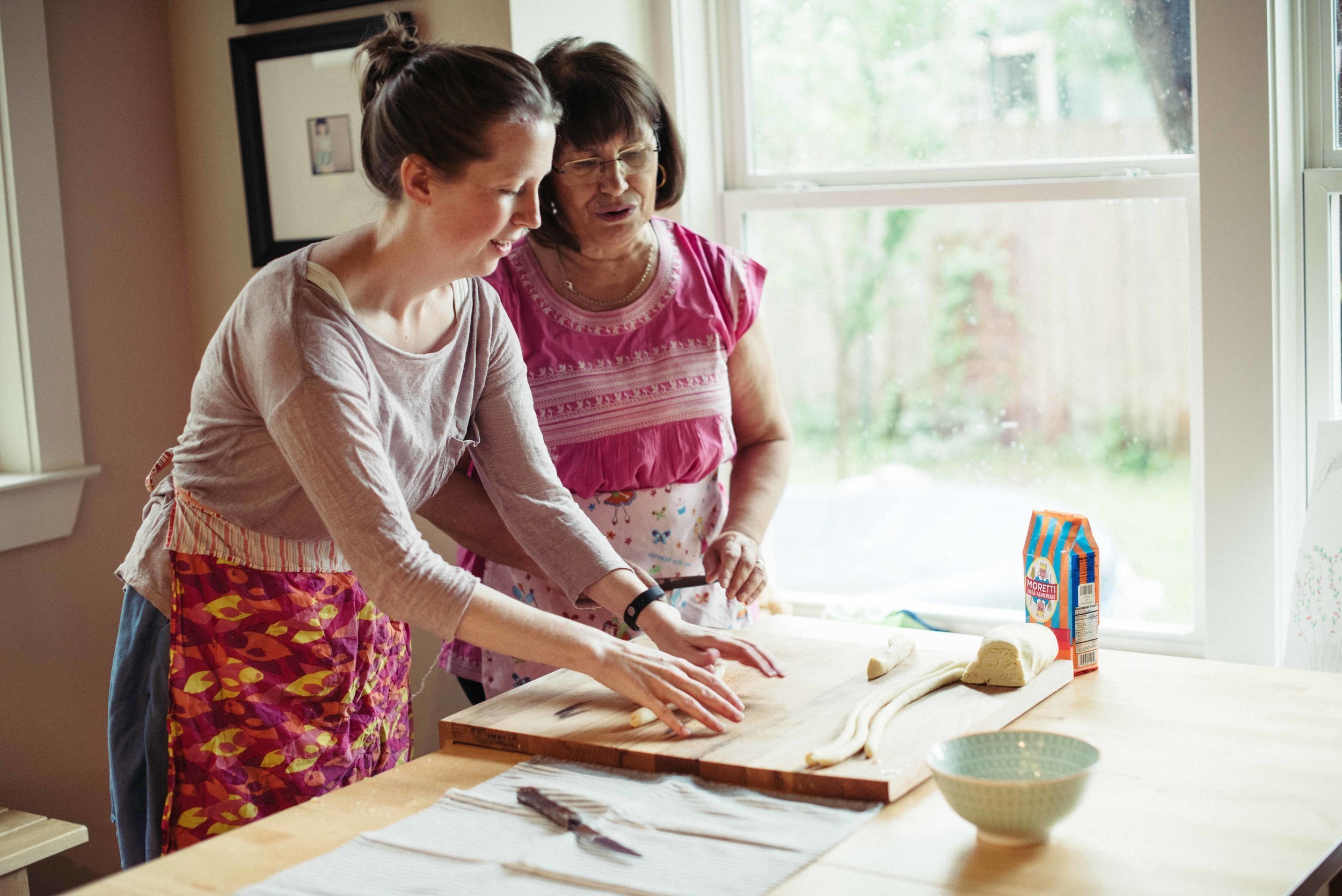 Two women wearing aprons are skillfully preparing food on a cutting board in a captivating food photography image..jpg