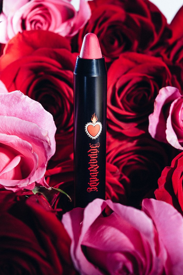 A lipstick stick with a heart on it is placed in front of a bunch of roses. Captured by a beauty product photographer.jpg