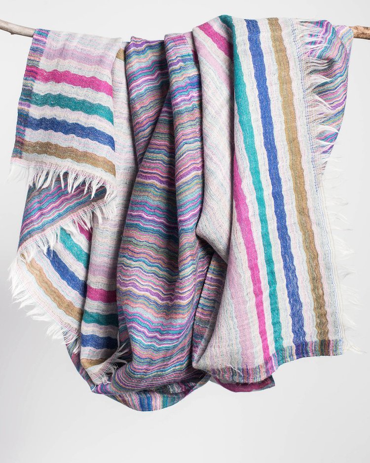 A vibrant striped blanket hanging on a clothesline for product photography adds a pop of color to the surroundings.jpg