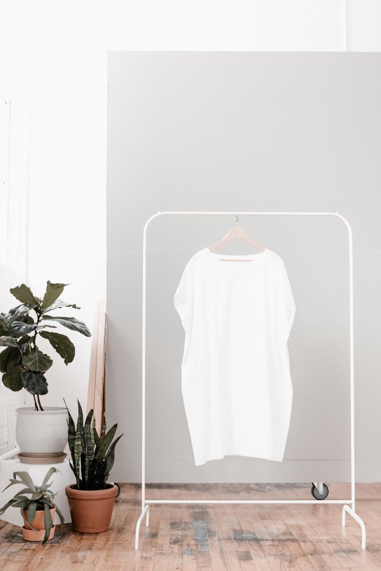 A white shirt on a clothes rack against a white wall, showcasing the best product photography.jpg