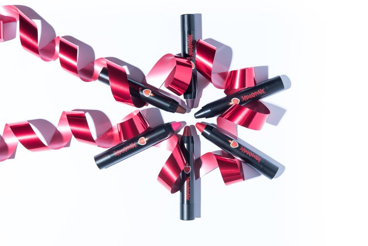 In cosmetic product photography, a circle is formed by a red ribbon and black lipstick.jpg