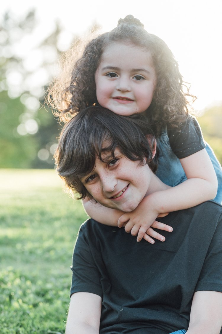 A brother and sisterl sitting on the grass in a family children photography session.jpg